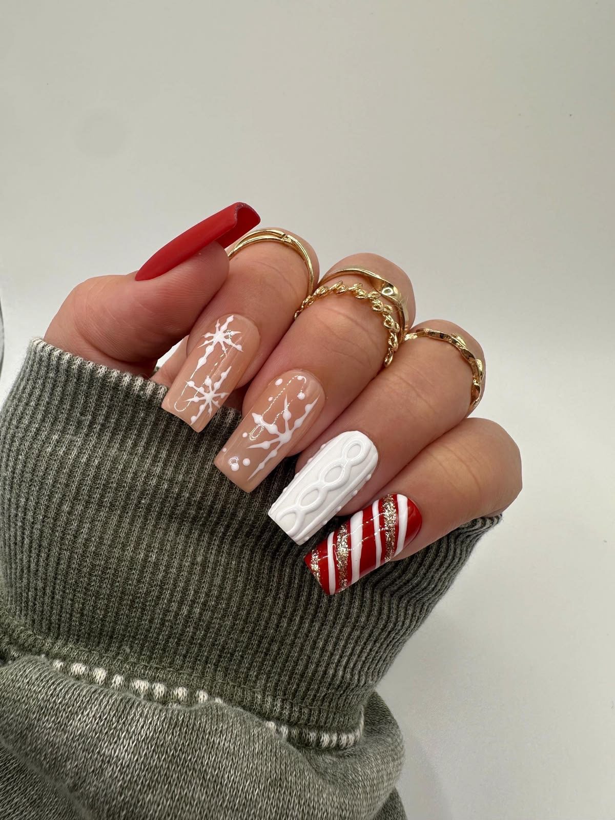 Christmas nails with white snowflakes, cable-knit texture, and red candy cane stripes