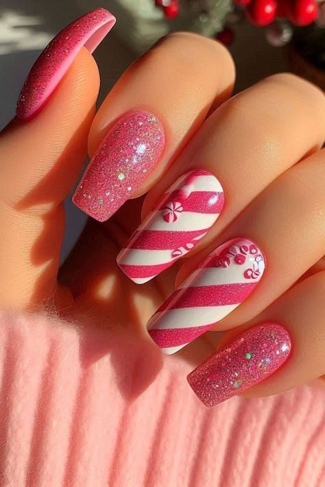Long pink glitter Christmas nails with white candy cane stripes and small peppermint candy details