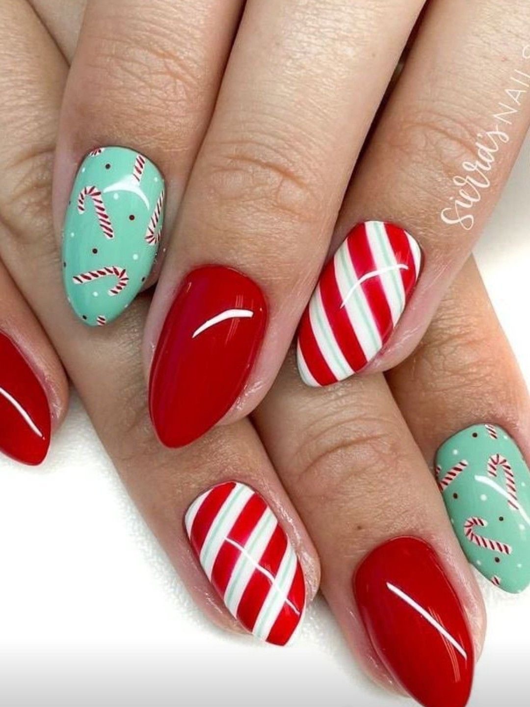 Rose gold glitter Christmas almond nails with white candy cane stripes and a delicate snowflake accent