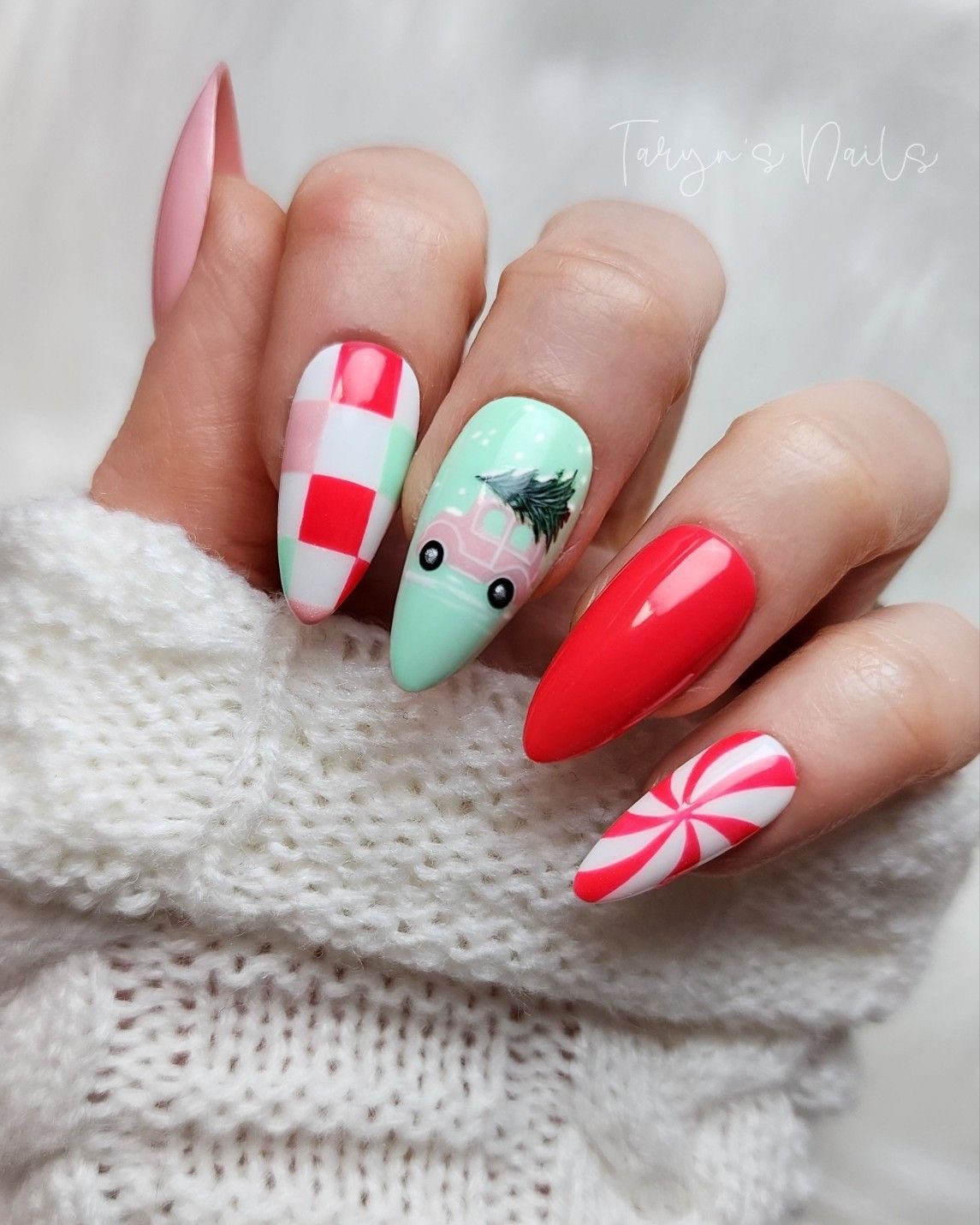 Colorful Christmas almond nails with peppermint swirls, a smiling Santa hat character, and pastel checkered patterns