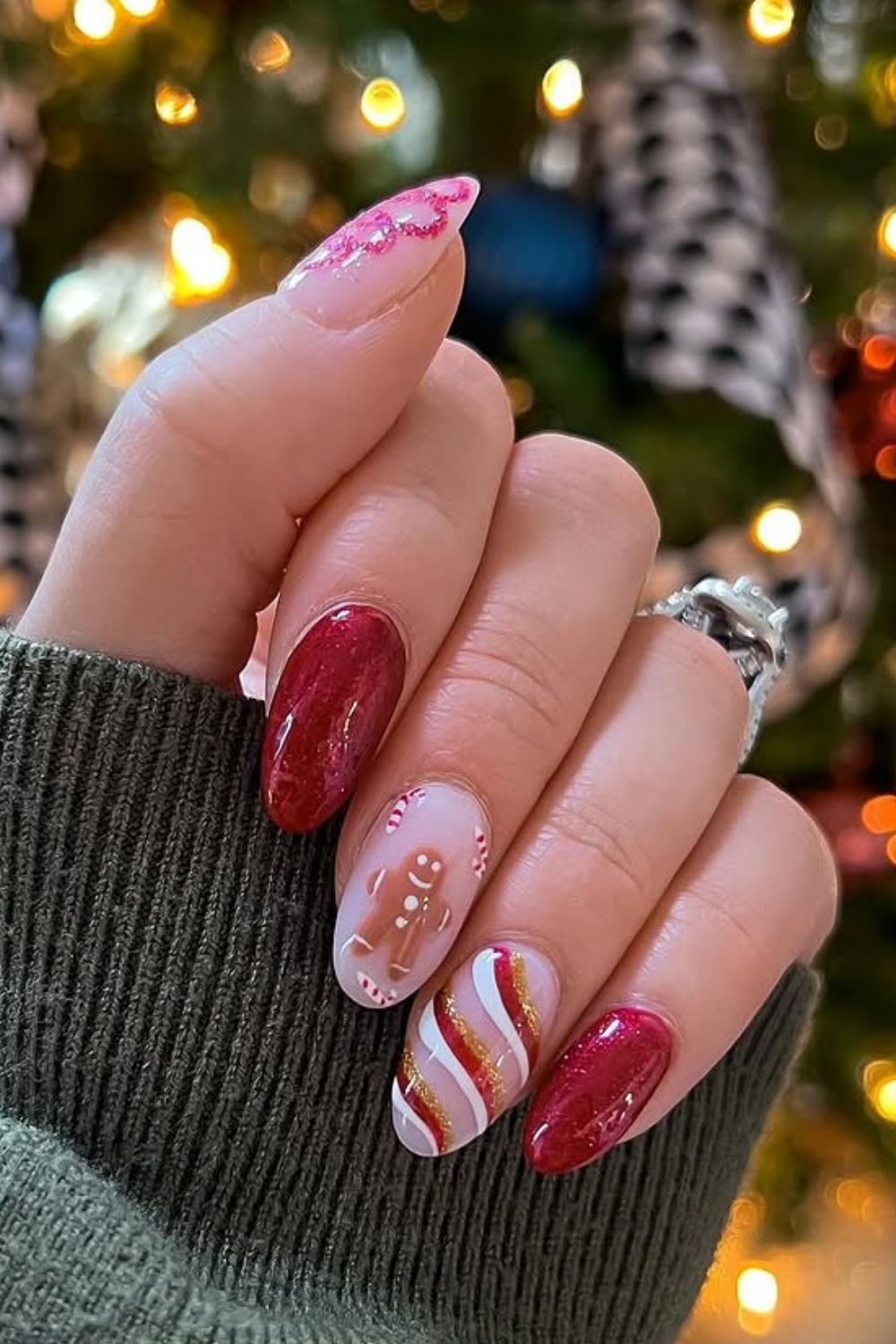 Hot pink Christmas almond nails with candy cane stripes, green glitter holly leaves, and red berry details