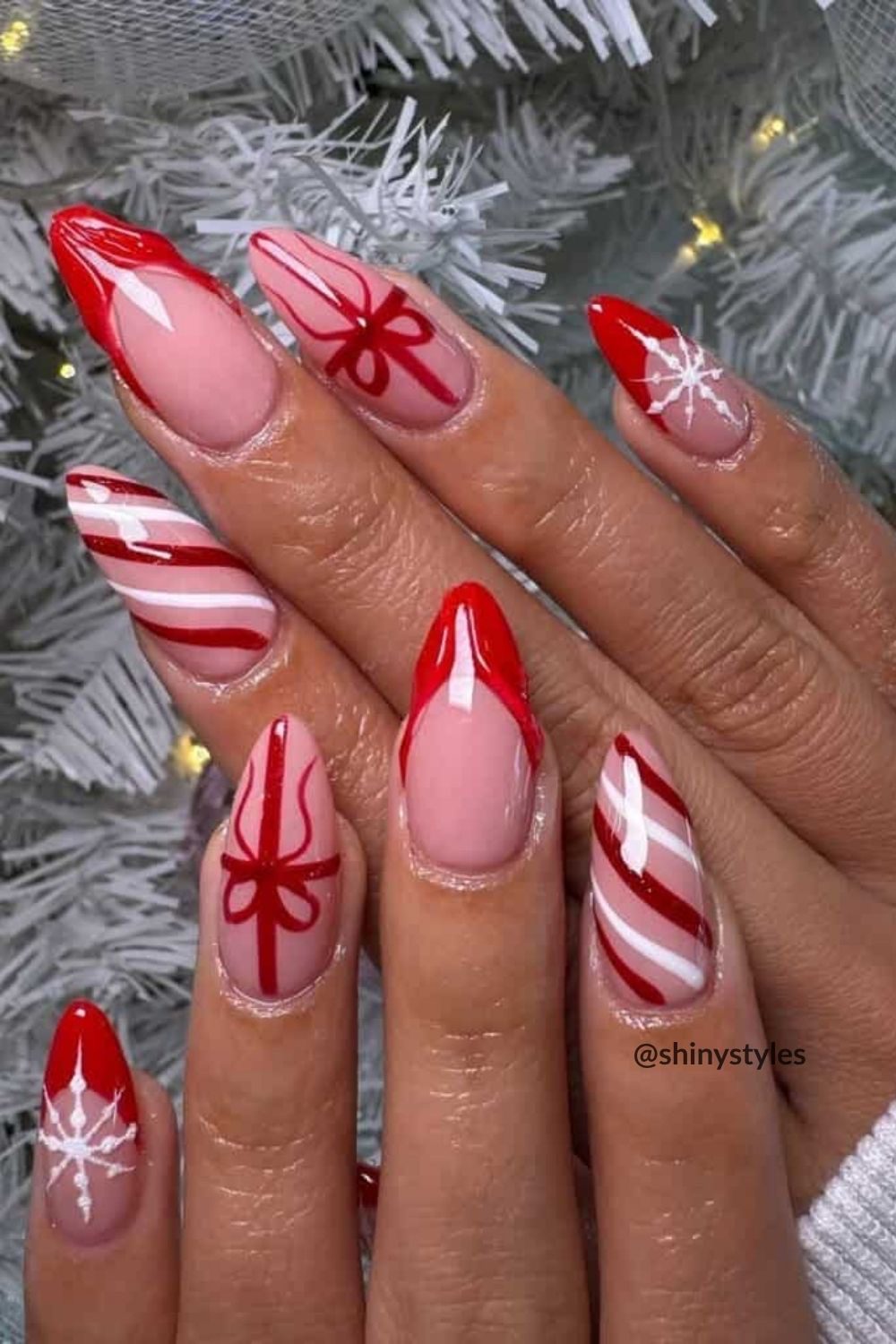 Christmas almond nails with a gingerbread man, red glitter polish, and red white and gold candy cane stripes