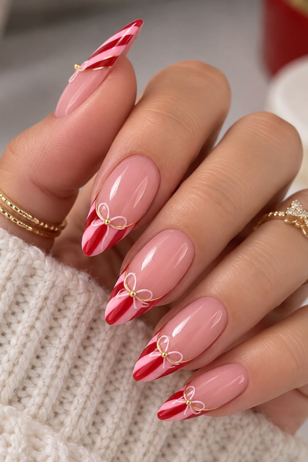 Glossy pink almond nails with red and pink candy cane French tips and delicate white bows