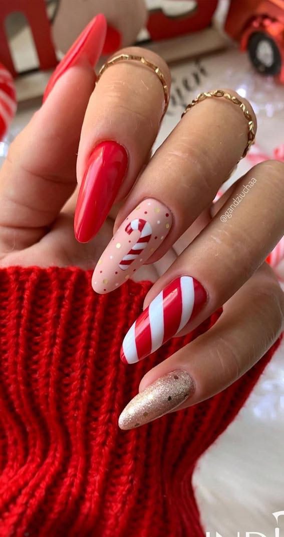 Red Christmas stiletto nails with a candy cane accent, gold glitter, and a tiny candy cane illustration