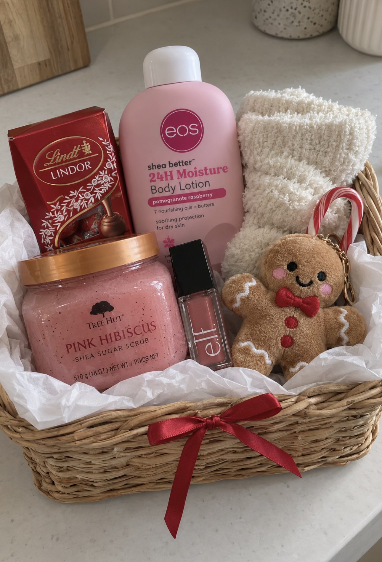 30 Thoughtful Christmas Gift Basket Ideas for Her 90 30 Thoughtful Christmas Gift Basket Ideas for Her Wicker Christmas basket with eos lotion, Tree Hut Pink Hibiscus scrub, Lindt chocolates, fluffy socks and a gingerbread plush