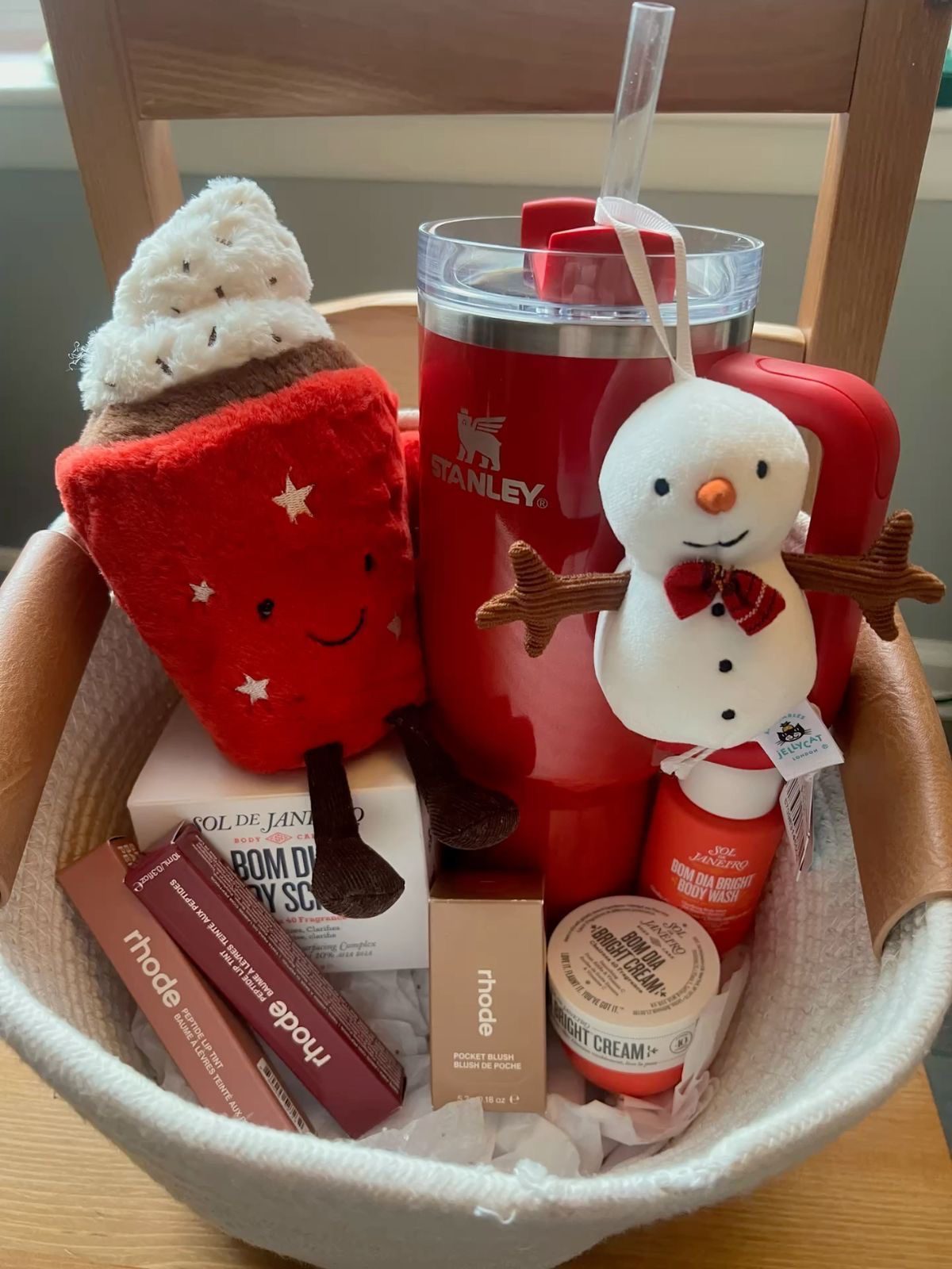 30 Thoughtful Christmas Gift Basket Ideas for Her 65 30 Thoughtful Christmas Gift Basket Ideas for Her Christmas basket with a red Stanley tumbler, Rhode and Sol de Janeiro products, and festive plush toys