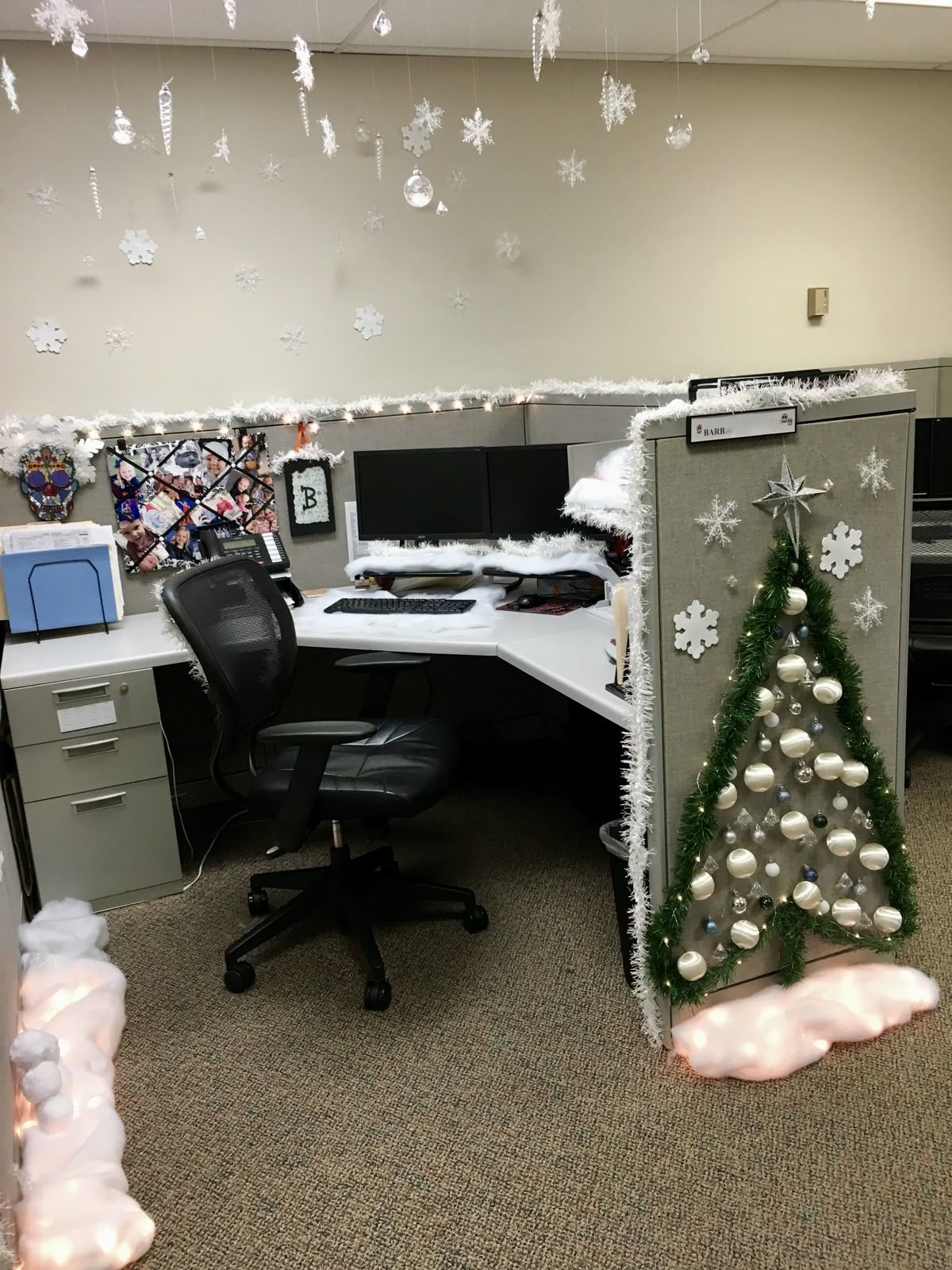 Winter wonderland office cubicle with white snowflakes, silver tinsel and a garland Christmas tree