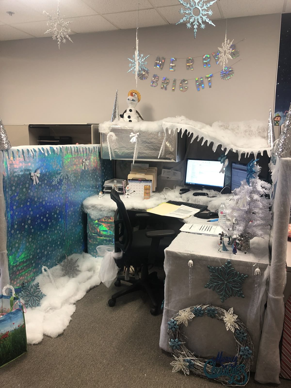 Frozen-inspired Christmas office cubicle with artificial snow, blue decorations and white Christmas tree