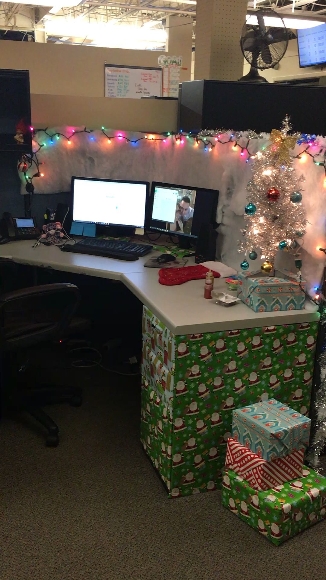 Christmas office cubicle decorated with Santa wrapping paper, colourful lights and silver tabletop tree