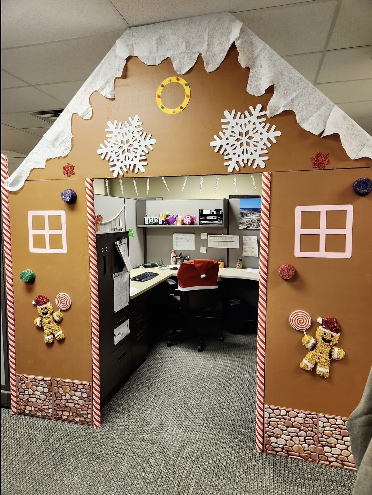 Office cubicle transformed into a giant gingerbread house with candy cane trim and snowflake decorations