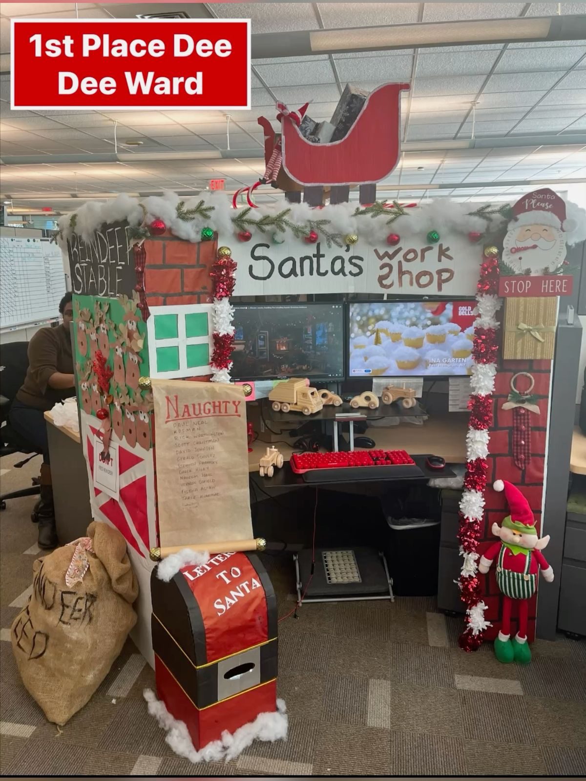 Santa's Workshop-themed Christmas office cubicle with sleigh, naughty list, reindeer stable and elf