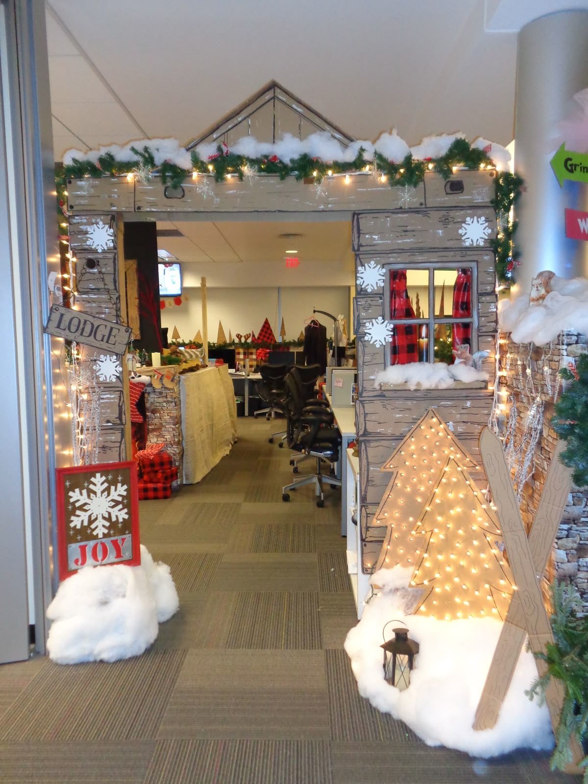 Christmas lodge-themed office entrance with snowy roof, wooden cabin details and warm fairy lights