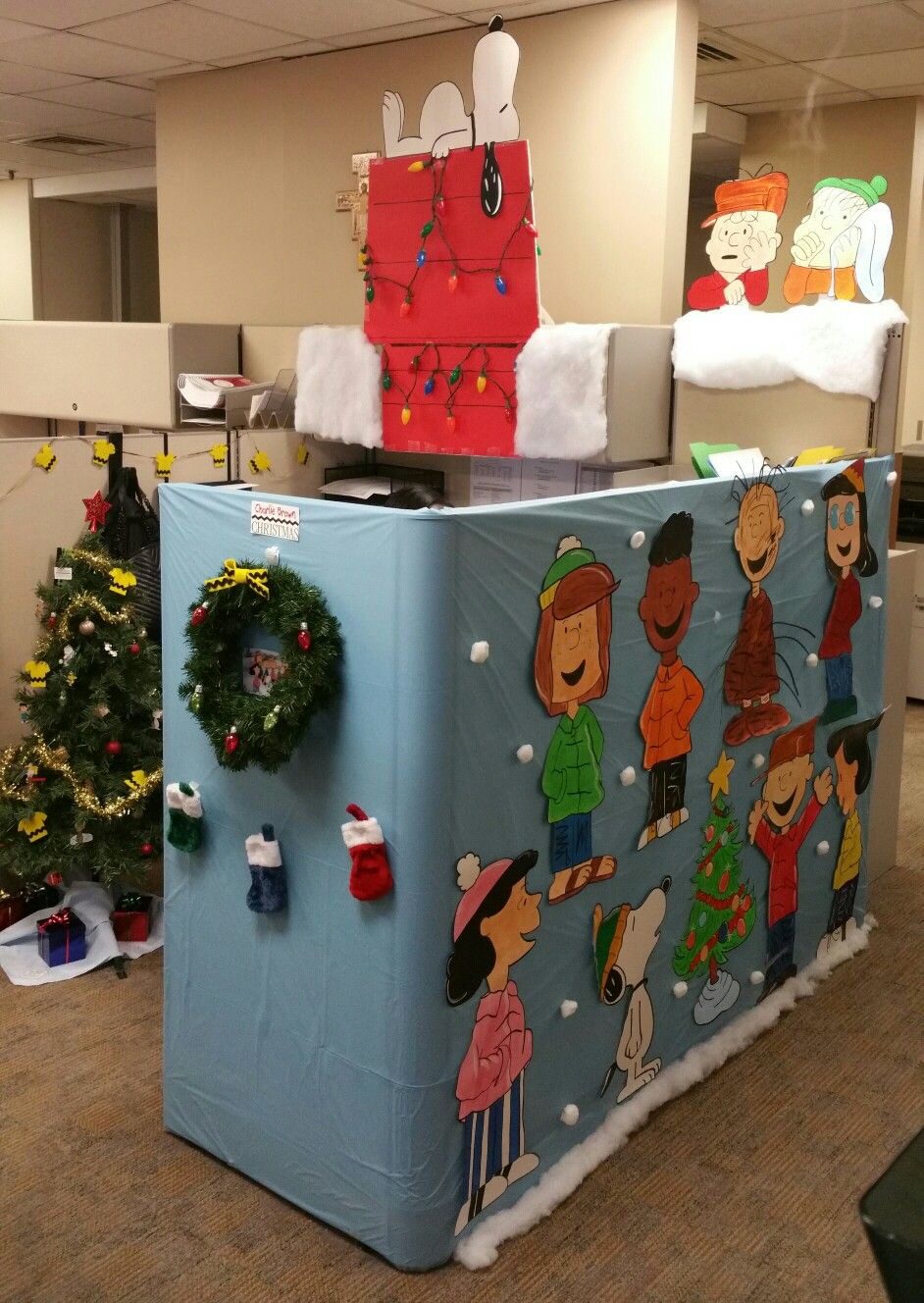 Charlie Brown Christmas-themed office cubicle with Peanuts characters, Snoopy doghouse and Christmas tree