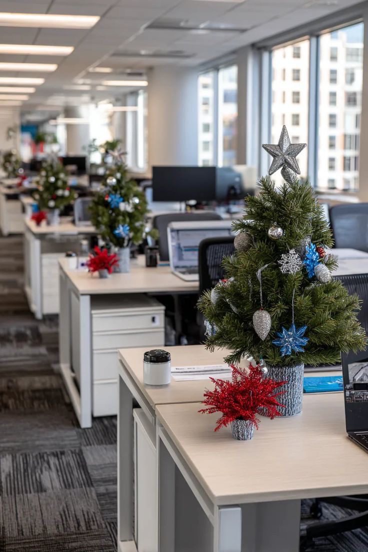 Modern open-plan office decorated with miniature Christmas trees and red festive flowers