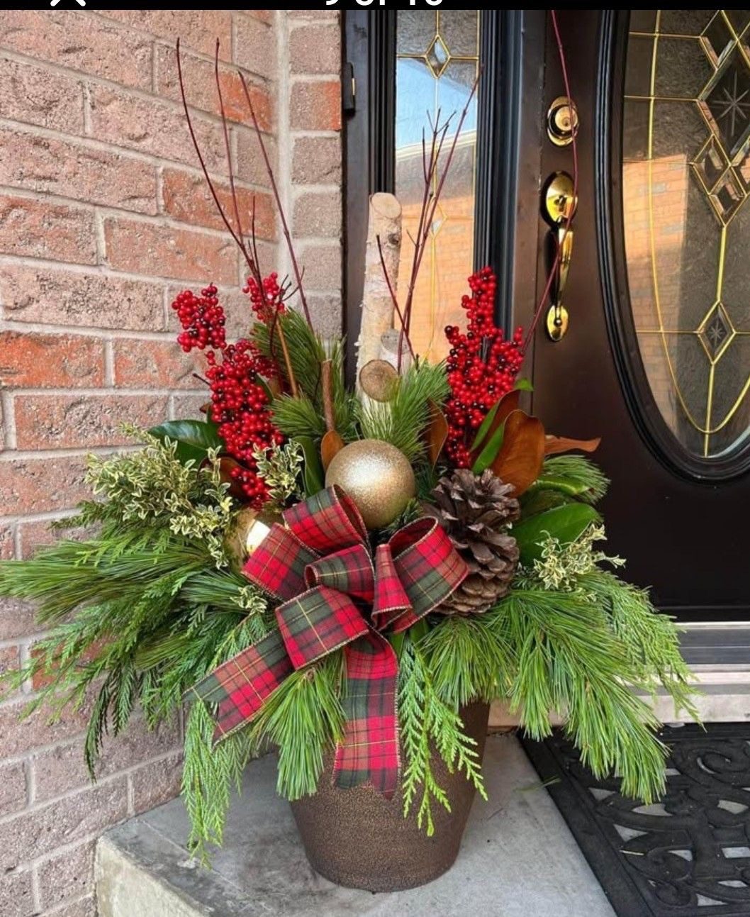 Classic Christmas planter with evergreen branches, red berries, gold ornament, pinecones and red plaid bow