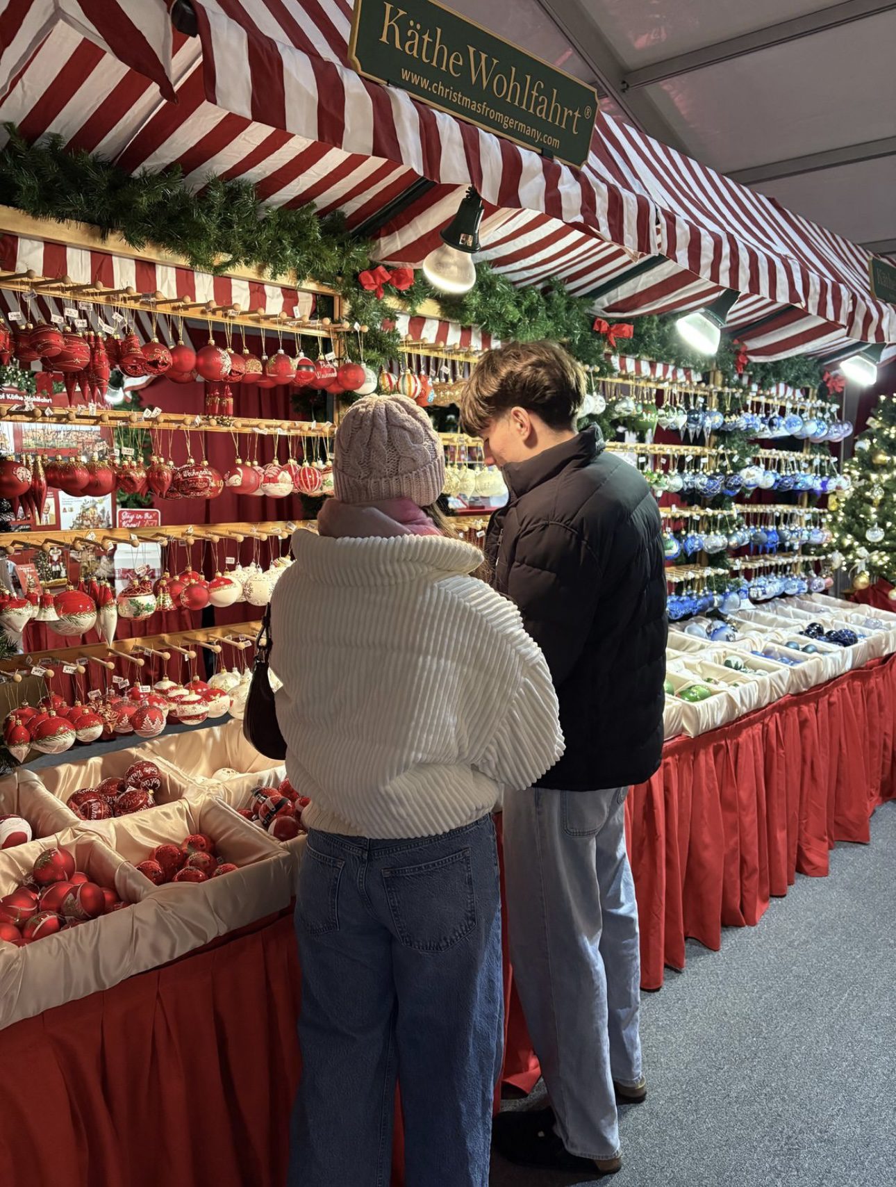 Couple browsing colourful ornaments at a Christmas market stall