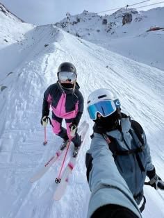 Couple wearing helmets and ski gear on a snowy mountain slope