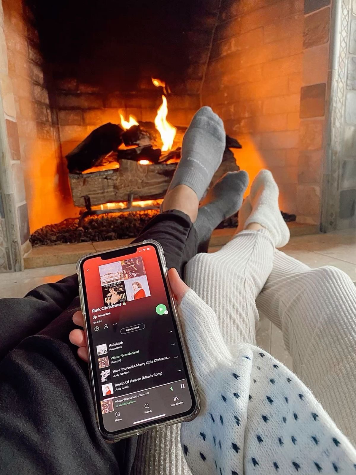 Couple relaxing beside a fireplace while listening to music on a phone
