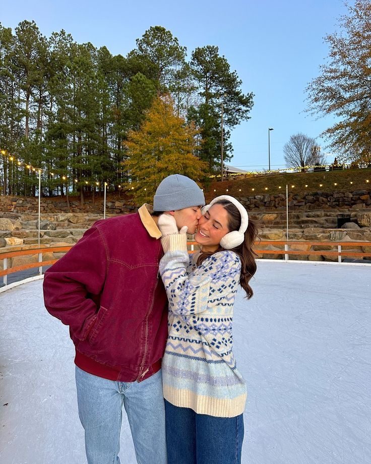 Couple sharing a kiss at an outdoor ice rink on a sunny winter day