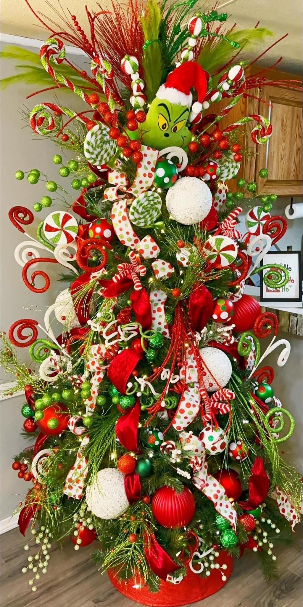 24 Fun Grinch Christmas Tree Ideas You'll Love 58 24 Fun Grinch Christmas Tree Ideas You'll Love Candy-themed Grinch Christmas tree with Santa hat topper, colourful swirls and red and green decorations