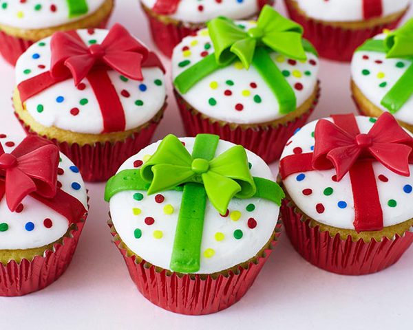 24 Easy & Creative Christmas Cupcakes to Try Right Now 64 24 Easy & Creative Christmas Cupcakes to Try Right Now Christmas present cupcakes decorated with white frosting, red and green fondant ribbons, and bows